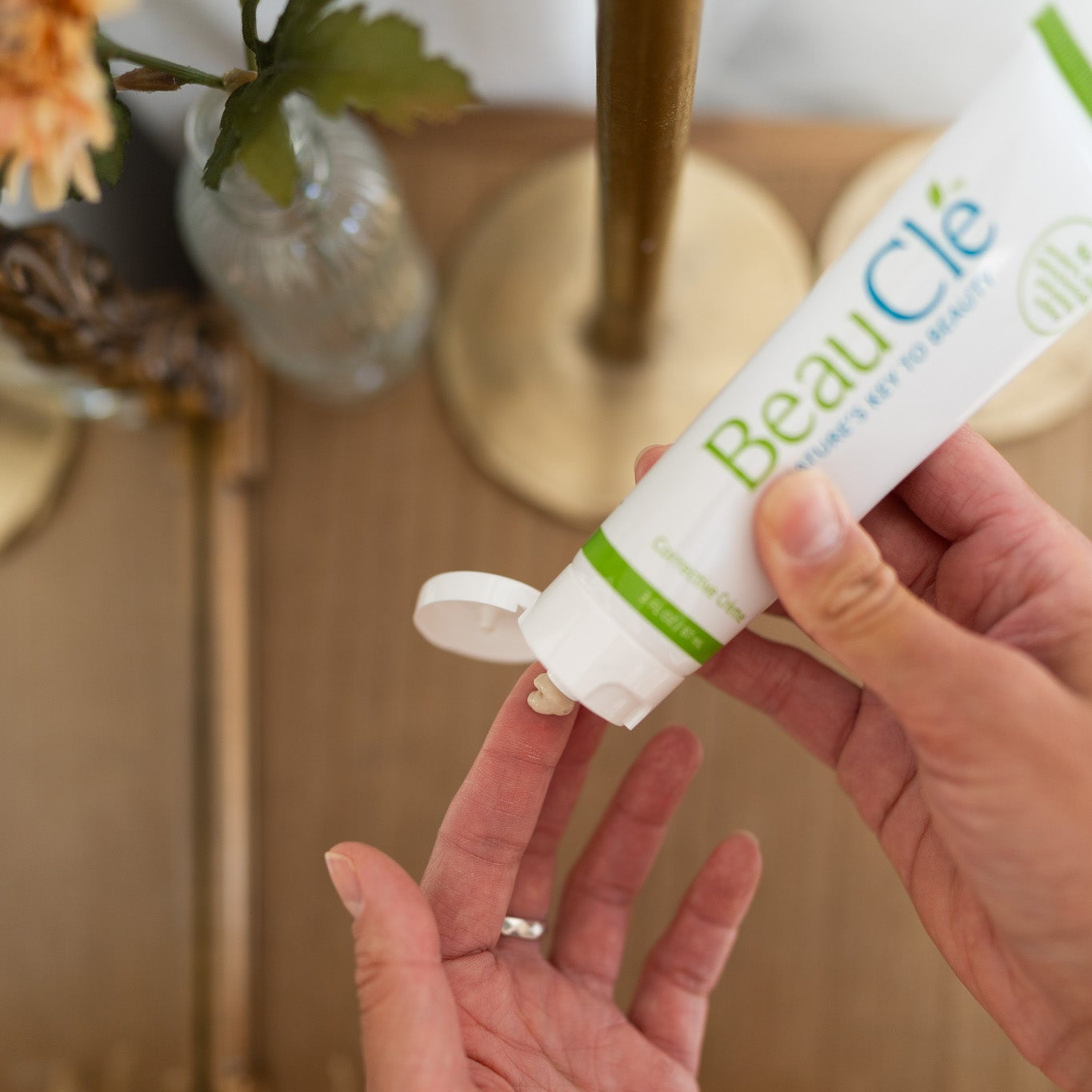 Person holding a tube of BeauClé product with a blurred background